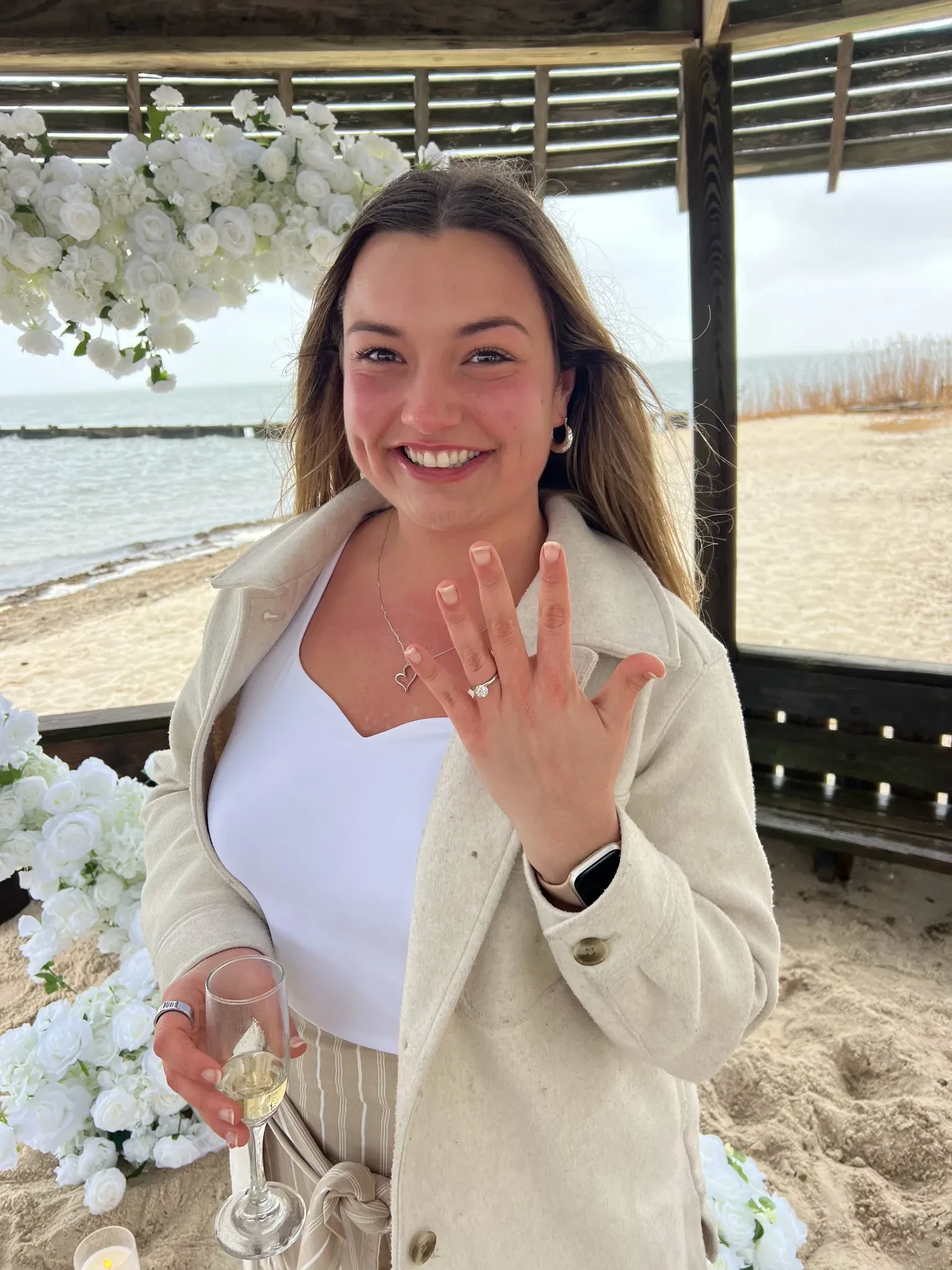 Woman showing engagement ring at beach gazebo